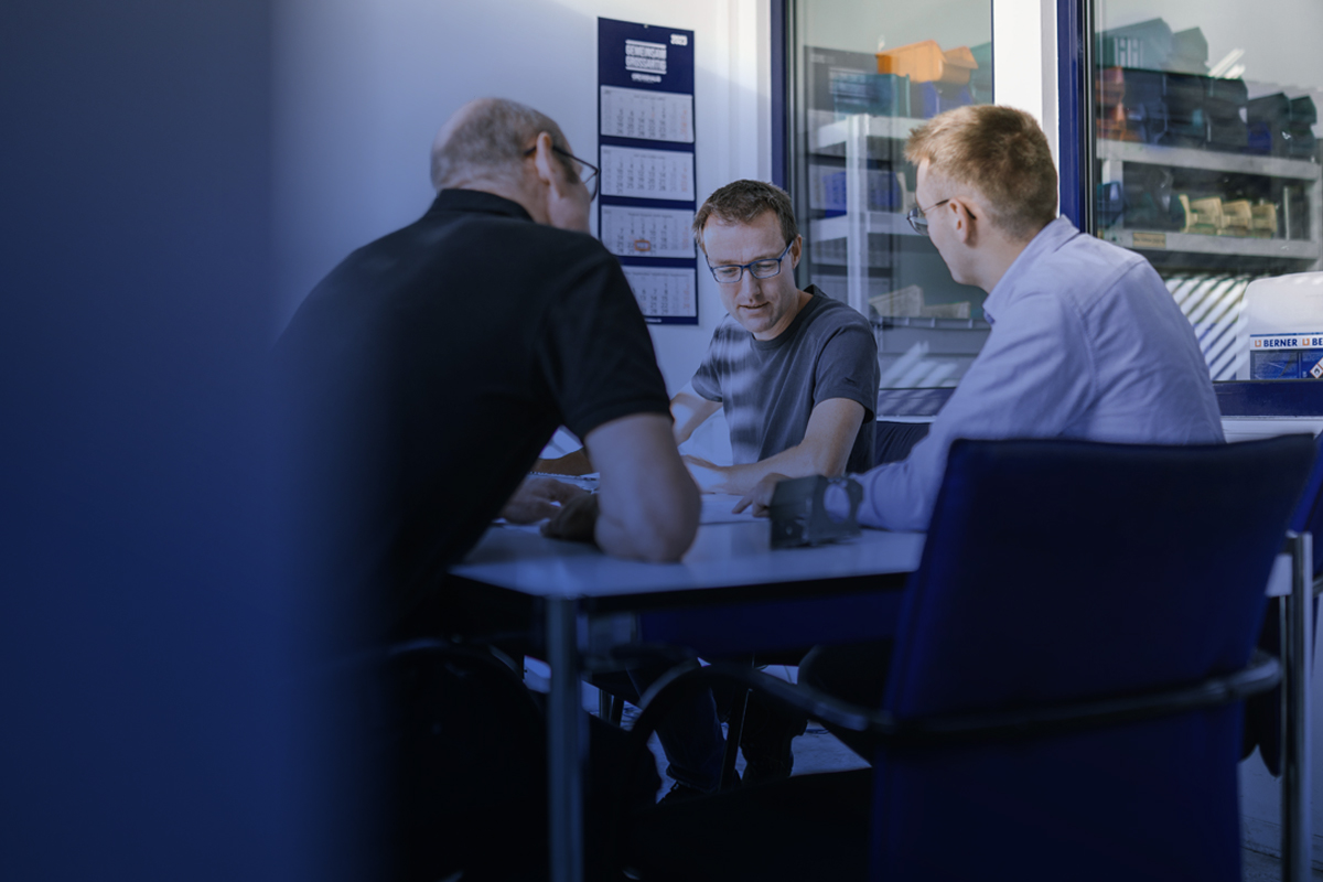 Mitarbeiter im technischen Umfeld bei einer gemeinsamen Besprechung am Arbeitsplatz.
